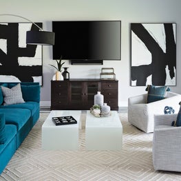White walls flanked by bold black and white artwork; teal oversized custom sofa.