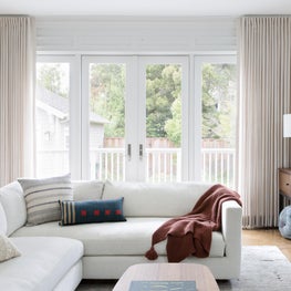Inviting living room with luxurious sofa and floor-to-ceiling draperies.