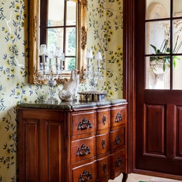 Colorful wallpaper & an antique walnut marble top chest is in the foyer.