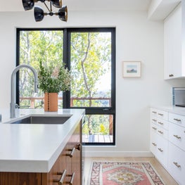 Bright kitchen with white cabinets and counter top, runner, and wooden island cabinets