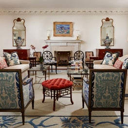 Custom sofas in this living room and a red bench are blended by antiques.