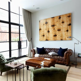 Townhouse living room with factory steel windows and tufted chesterfield sofa