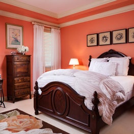The contrast of peach walls and a carved solid walnut bed warms this bedroom