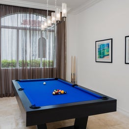 Expansive Decadent Waterfront, pool room, pool table, marble floors, blue pool table, modern chandelier, picture window, sheer curtains