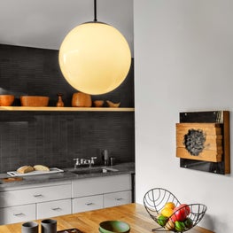 Kitchen with orb pendant, cool grey walls, open shelving, wood block island