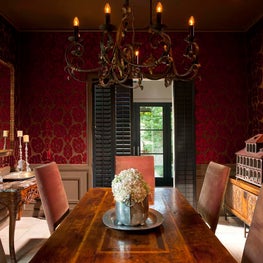 Eclectic dining room emphasized by a bold red and gold wallcovering. 
