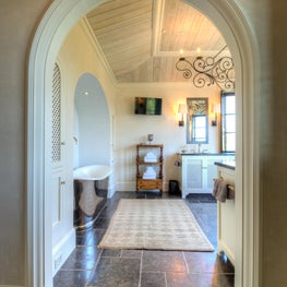 Master Bathroom Arched Opening with Silver Apron Tub on a Black Stone Floor