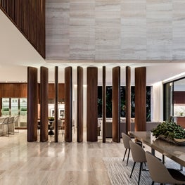Vertical walnut beams elegantly swiveling to separate formal and casual areas