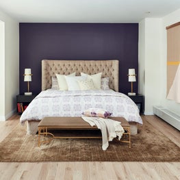 Manhattan contemporary bedroom with purple accent wall and geometric art.