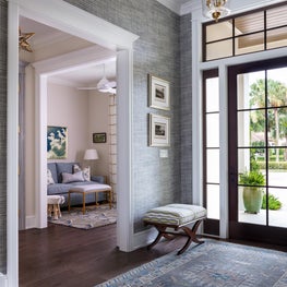 The entry hall showcases textured blue grey wallpaper by Phillip Jeffreys.