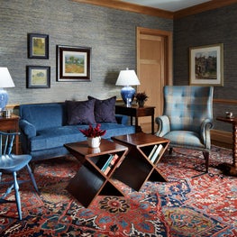 Lake Geneva Salon. Cozy blue seating with navy grasscloth walls, red area rug, plaid wing chair and blue windsor chair.