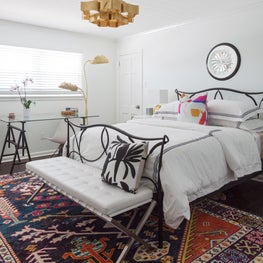 Bohemian Guest Bedroom with multi colored rug and metal bed 