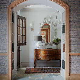 Lake Geneva Foyer. Dutch door entry with antiques, grasscloth walls & plaster white oak leaf mirror.