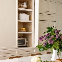 Custom millwork hides a day pantry as well as a fridge and freezer in this bespoke kitchen.