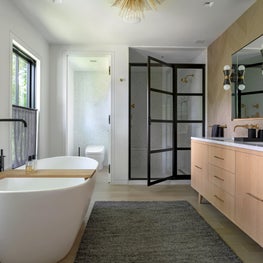 Master bathroom with white oak vanity and glass shower door with black frame