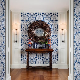 Vibrant blue and white wallpaper adds a sense of liveliness to this entry hall. 
