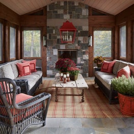 Lake Geneva Porch. Screened-in porch with red accents and stone fireplace. Antiques & black wicker on natural slate pavers.