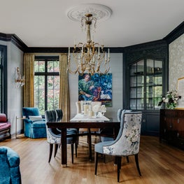 Blue and purple dining room with dark wood table and brass chandelier.