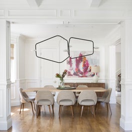 Bright dining room with modern chandelier, midcentury chairs, custom wainscot.