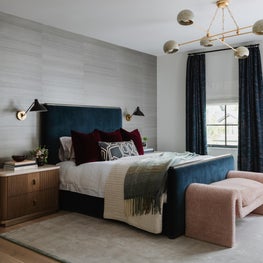 Portfolio: A moody bedroom combines a channel-upholstered bed, textured wallcovering, sculptural lighting, and rich jewel tones with tailored details.