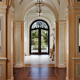 Bronze and glass front door seen across a gallery and entry hall