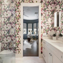 Flowery wallpaper adds a whimsical ambiance to this white powder room.