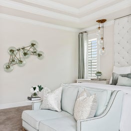 Handblown glass wall art in serene white & mint hued master bedroom w/seating. 