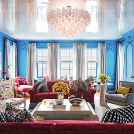 Bright cerulean blue living room with art deco barbell chandelier