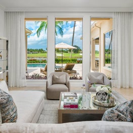 Expansive Decadent Waterfront, living room, white sectional, gray club chairs, chrome bookshelves, mirrored coffee table