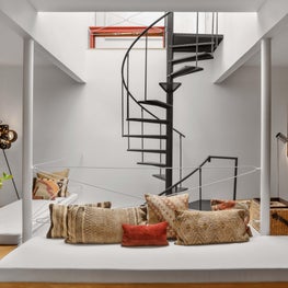 Basement family room with spiral staircase, mid-century pieces in modern space