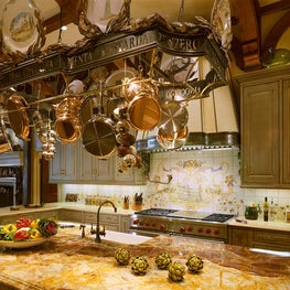 Suspended above the island is a hand-forged, iron pot rack adorned with Italian names of herbs.  The plaster and steel range hood repeats the Italian herbal detail and creates a focal point while counterpointing the classic style of the Wolf range.