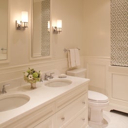 Clean, white bathroom with blue geometric roman shade