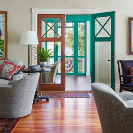 Historic Lake House Great Room. Classic Persian rugs with natural grasscloth walls & screened porch with green trim.