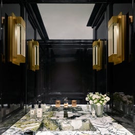 With lacquered-like black walls and a one-of-a-kind marble floating sink, this small space is filled to the brim with glam.