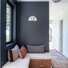 Hallway with built-in banquette and dark blue-grey walls