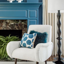 Blue Fire Place with White Accent Chair and Teal Blue Textured Throw Pillow