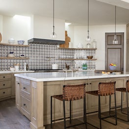 This kitchen includes Moroccan mosaic tiles and a plaster hood with steel band