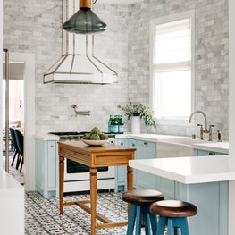 Light blue transitional kitchen with patterned tile floors and white appliances