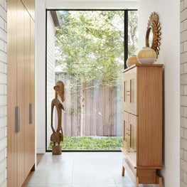 A view of a side garden with antique sculpture and antique Biedermier chair with Tiger Velvet by Brunschwig & Fils. Featured in Papercity.