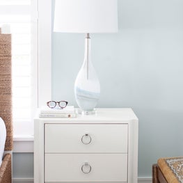 White grasscloth side table in a beach house guest bedroom