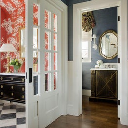 Foyer with checkered floor, red printed wallpaper; blue statement powder room