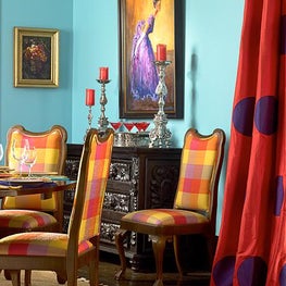In this blue walled dining room bright colors were used to pop the fabrics.