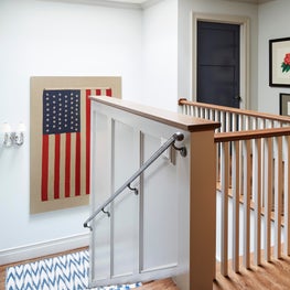 Lake Geneva Stair/Hall. 48 star flag hangs over blue and white ikat stair runner with gray trim & navy doors.