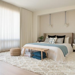 Modern white master bedroom w/ blue and black accents, shag rug, organic details