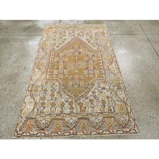 An antique Turkish Ghiordes rug. The square-winged salmon field is pointed above and below and contains several ewers and...