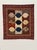 A hand-stitched and machine-stitched gridded layout creates nine distinct square sections of a snowball block variant a...