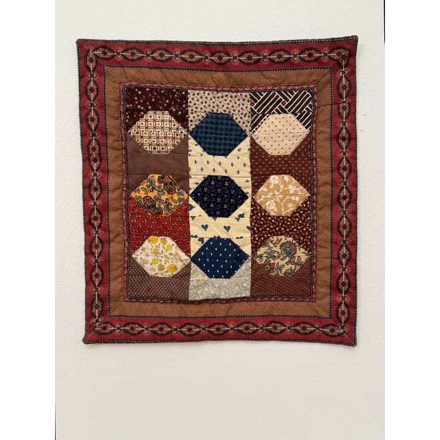 A hand-stitched and machine-stitched gridded layout creates nine distinct square sections of a snowball block variant a...
