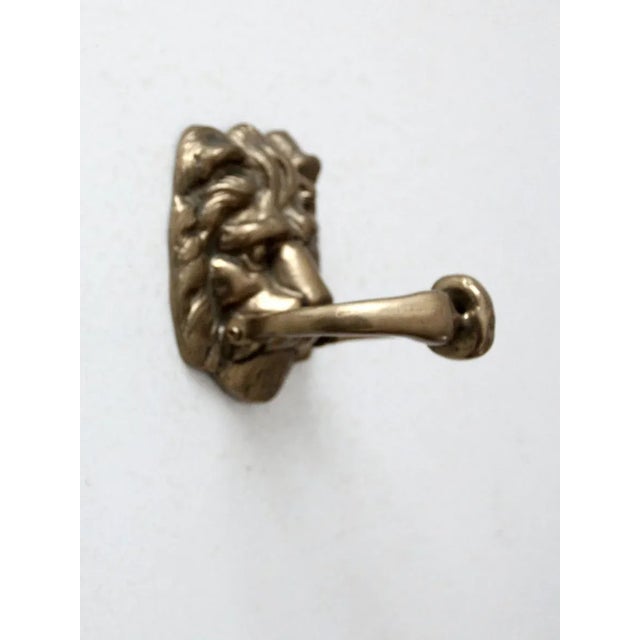 This is a vintage brass door knocker. Shaped as a lion's head, the knocker features a swinging bar handle held in the...