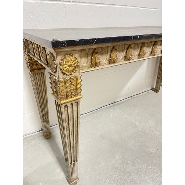 A sleek console table with silver and gold leaf finish with a well figured black marble top made by Marge Carson Furniture...