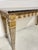 A sleek console table with silver and gold leaf finish with a well figured black marble top made by Marge Carson Furniture...